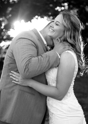 A black and white wedding photo capturing a romantic moment outdoors.