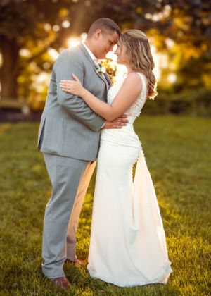 A bride and groom embrace during golden hour sunset in a romantic outdoor wedding photo.