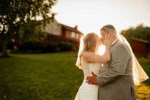 Romantic sunset wedding portrait with red barn in background during golden hour.