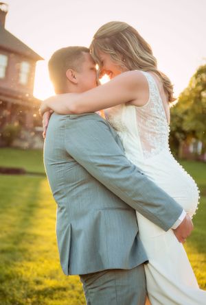 Romantic sunset wedding photo of couple embracing outdoors with warm golden light.