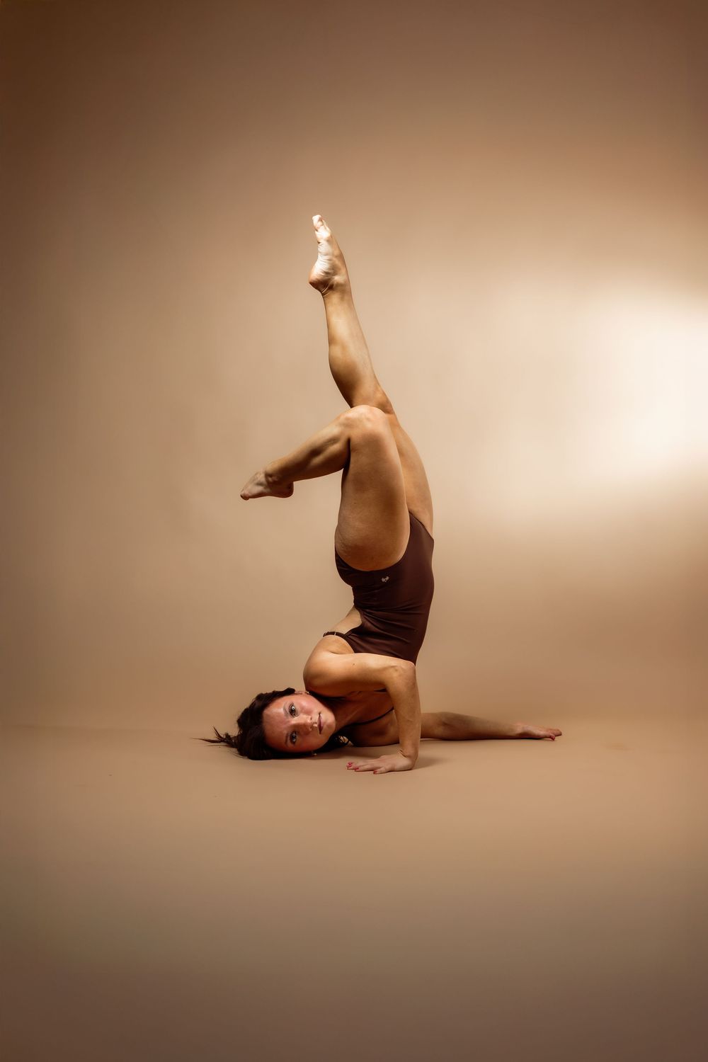A dancer performs a graceful sequence of movements on the floor in sepia-toned lighting.