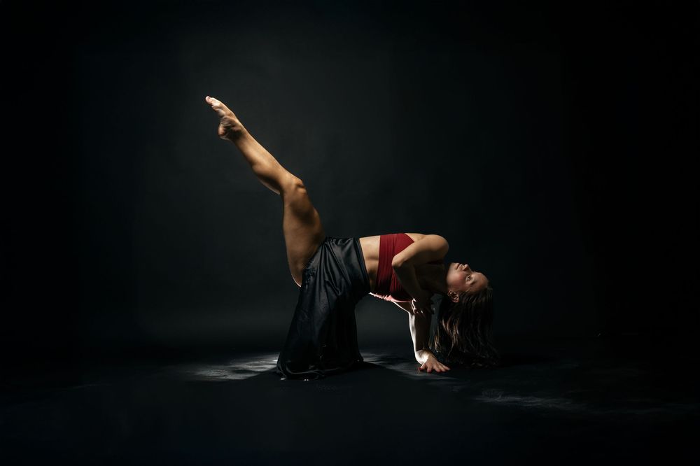 A dramatic sequence of a dancer in black performing a dynamic contemporary dance movement against a dark background.