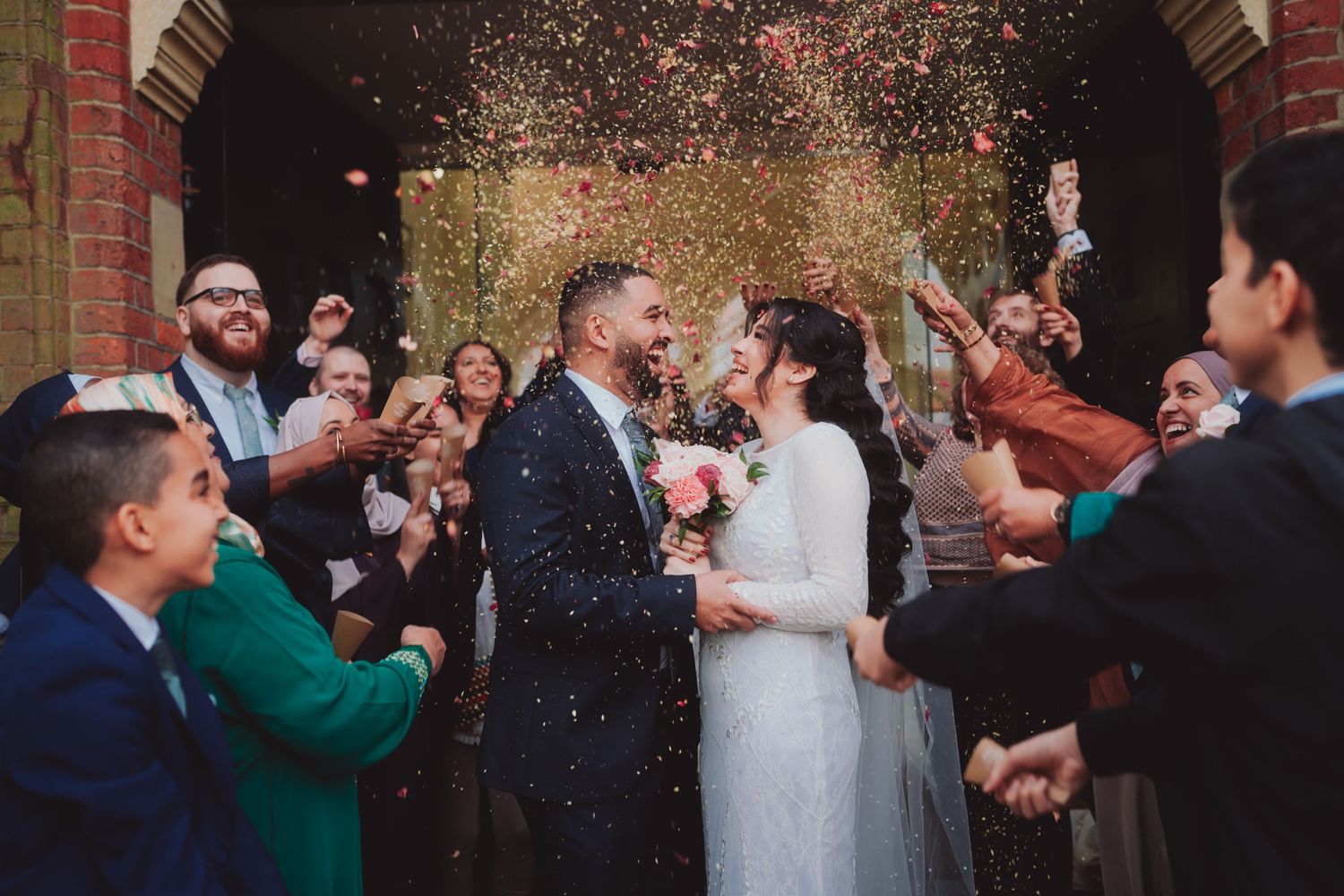 Wedding celebration with confetti shower and guests cheering at ceremony exit.