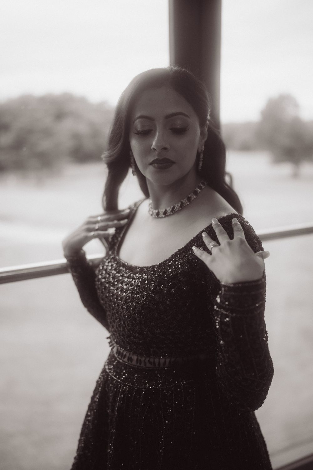 Dramatic black and white portrait of a woman in a beaded gown and statement necklace.