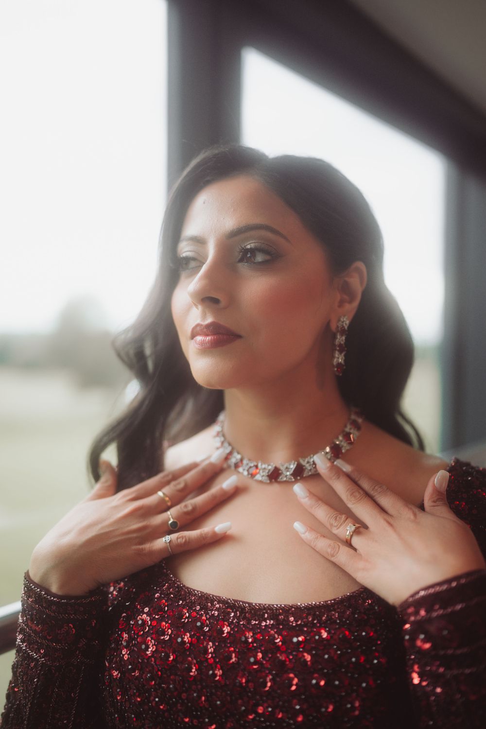 Glamorous portrait of a woman in a sparkly red dress wearing elegant jewelry.