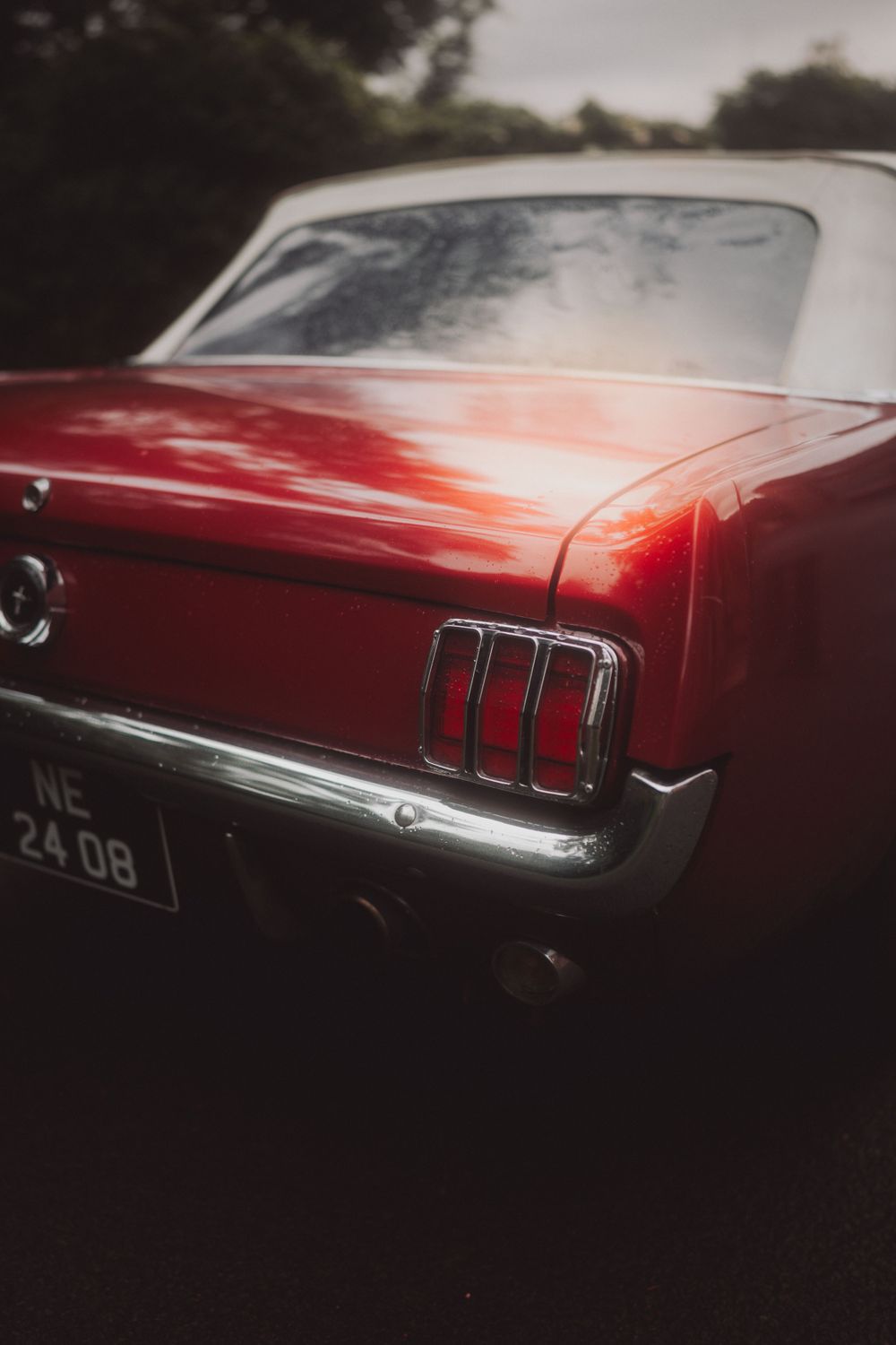 Close-up view of a classic red Ford Mustang's rear tail lights and chrome trim.