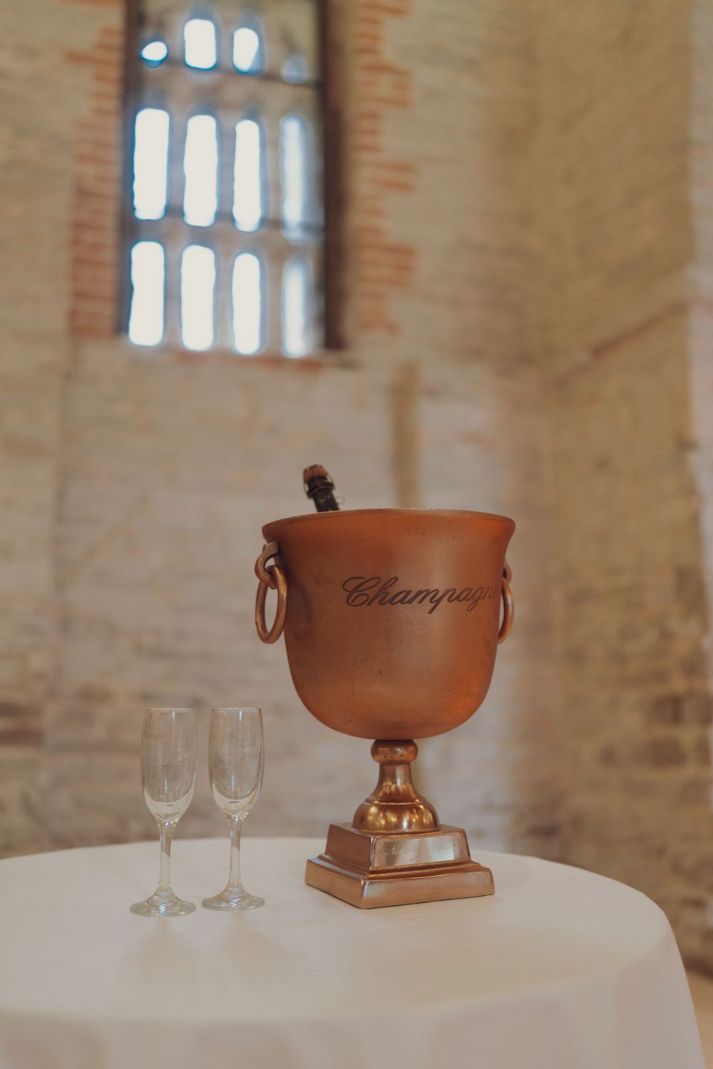 Elegant champagne trophy and wine glasses displayed on white tablecloth in historic venue.