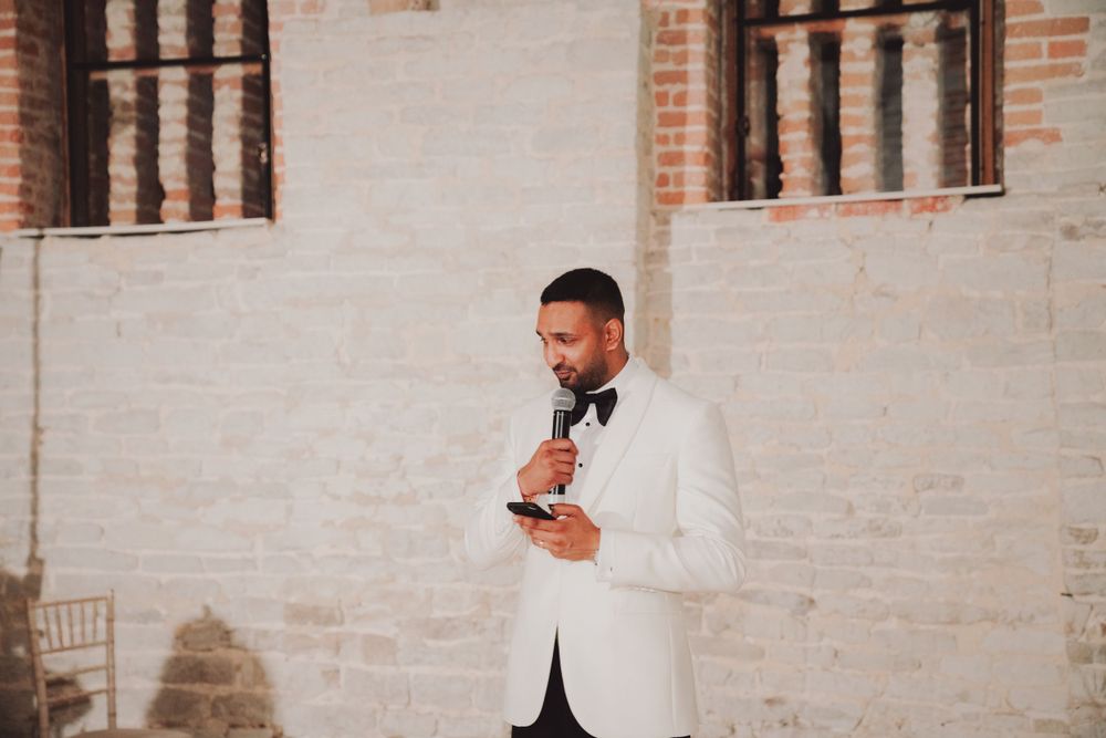 Man in white tuxedo jacket gives speech at formal event.