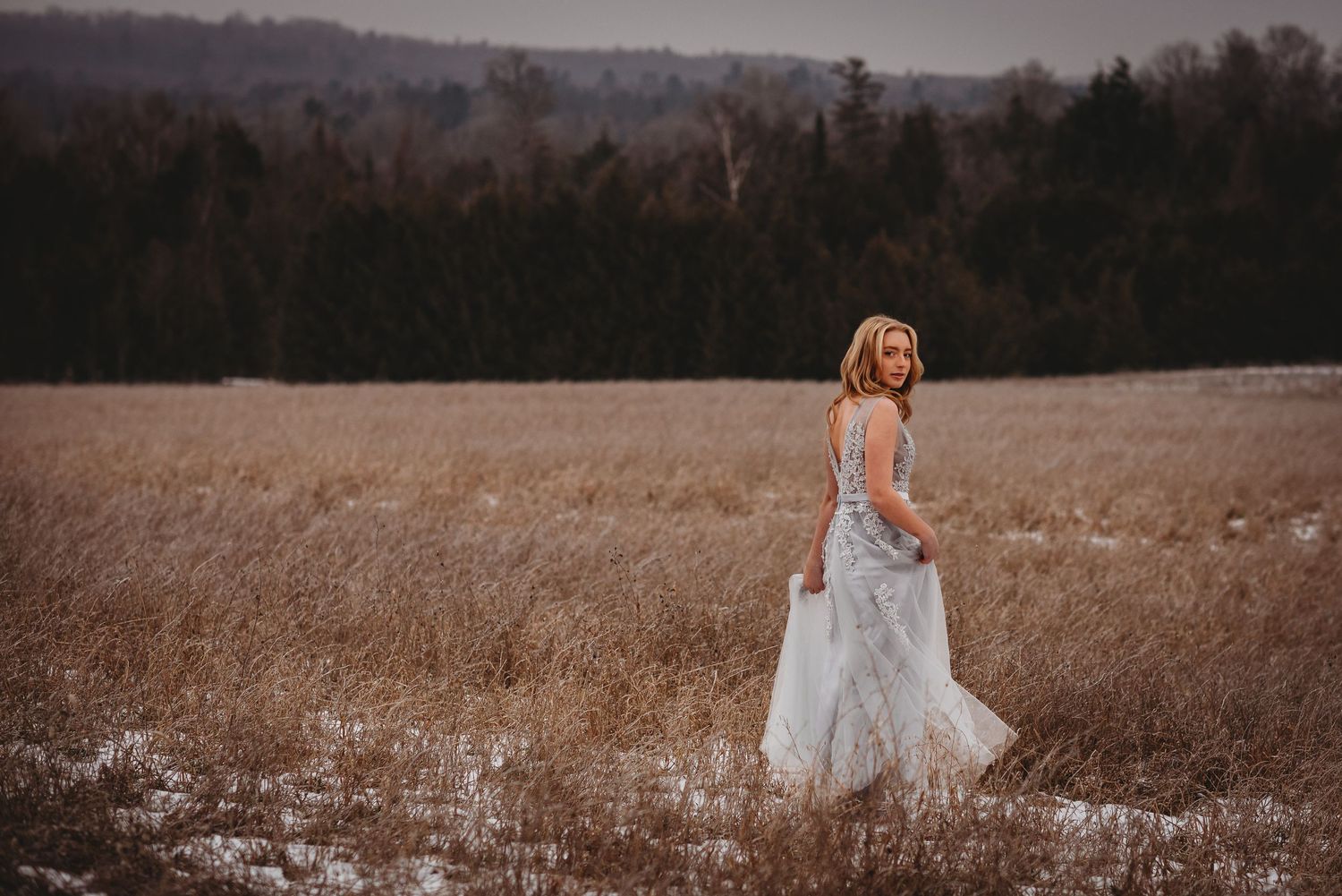 Winter fairytale-inspired photo of a girl in blue gown running across snowy field in Pontypool, Ontario.
