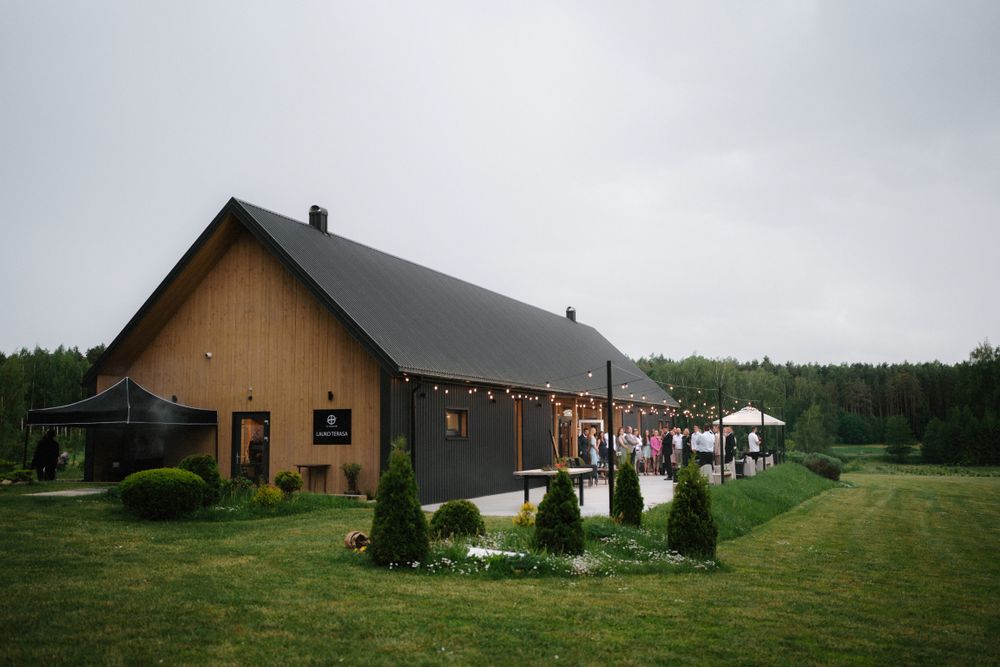 Panoramic view of rustic barn-style buildings set against a cloudy countryside landscape.