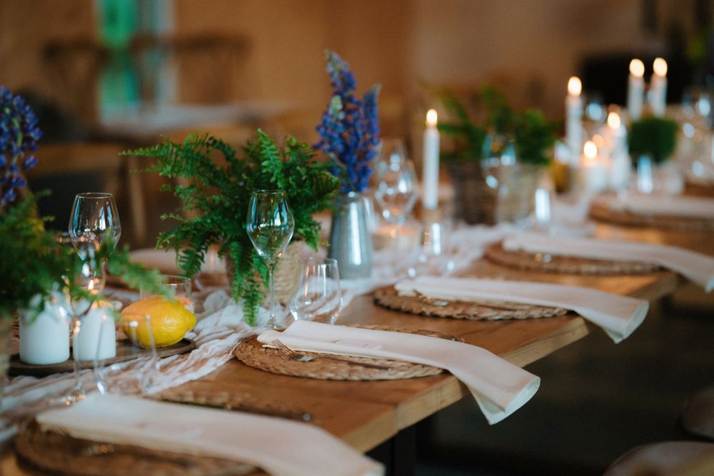 Rustic wedding table decor with blue flowers, white linens, and woven charger plates.