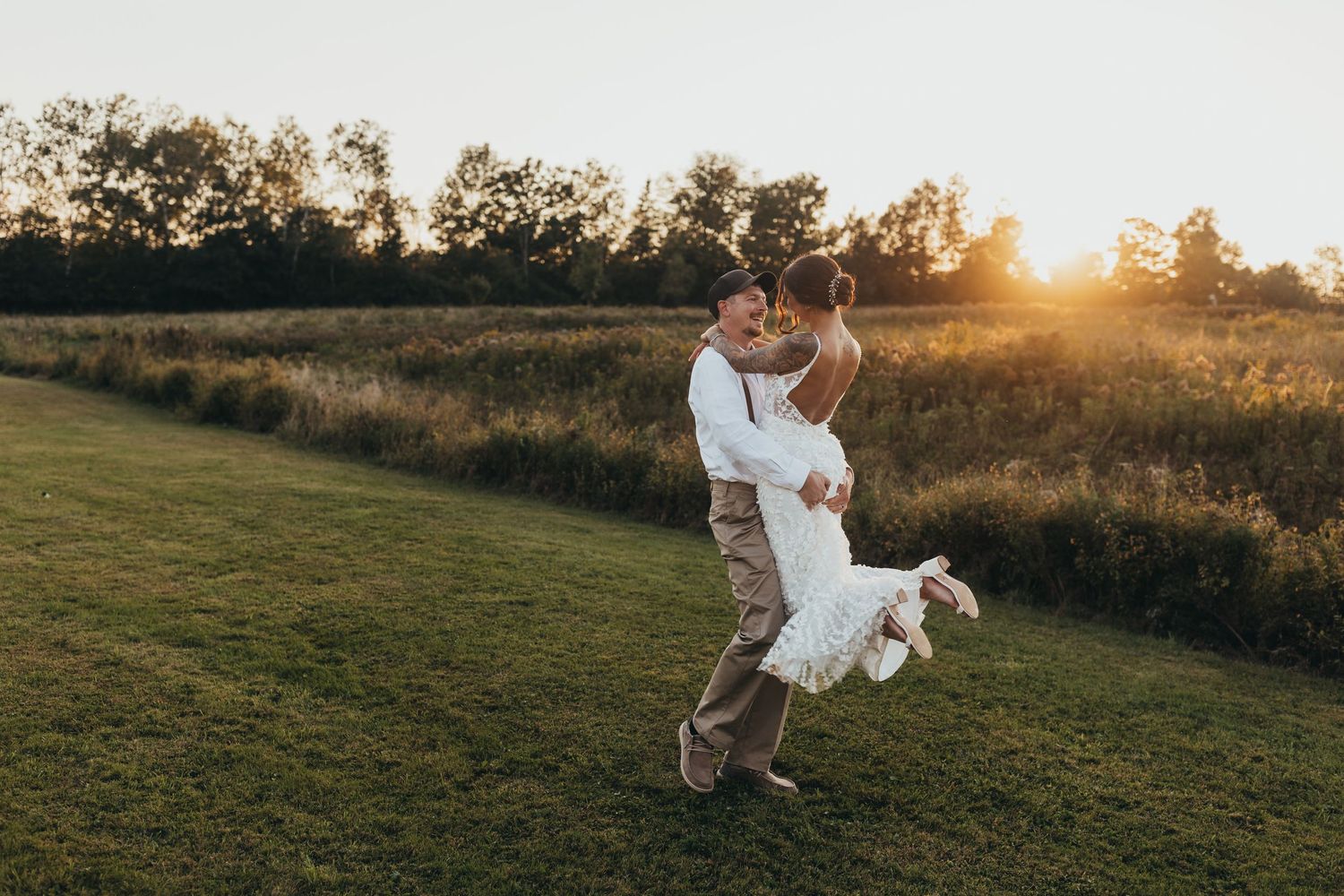 Sunset silhouettes of couple playfully running and jumping in a grassy field.