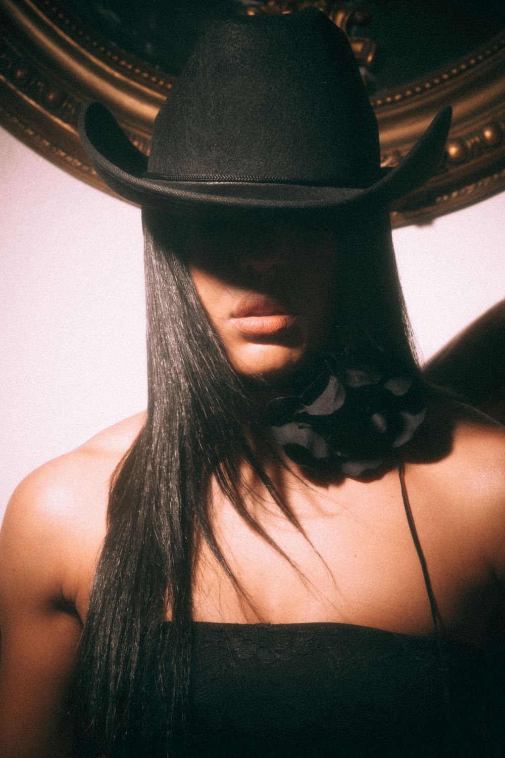 Stylized portrait with black hat and choker against golden mirror frame.