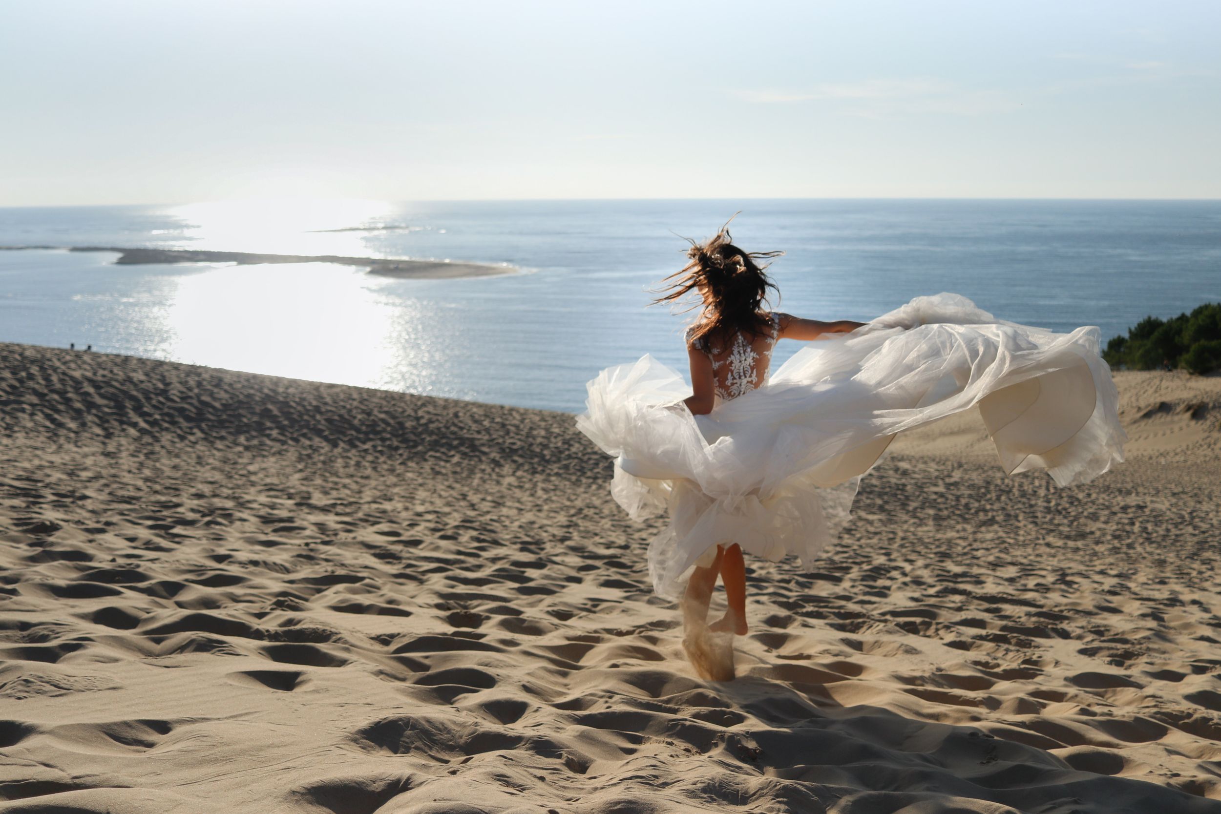 A flowing white dress billows in the wind as someone dances on a sandy beach at sunset.
wedding photo sevilla
retrato playa
mariage à la pla