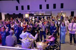 Large crowd of people gathered and celebrating together inside a spacious event venue.