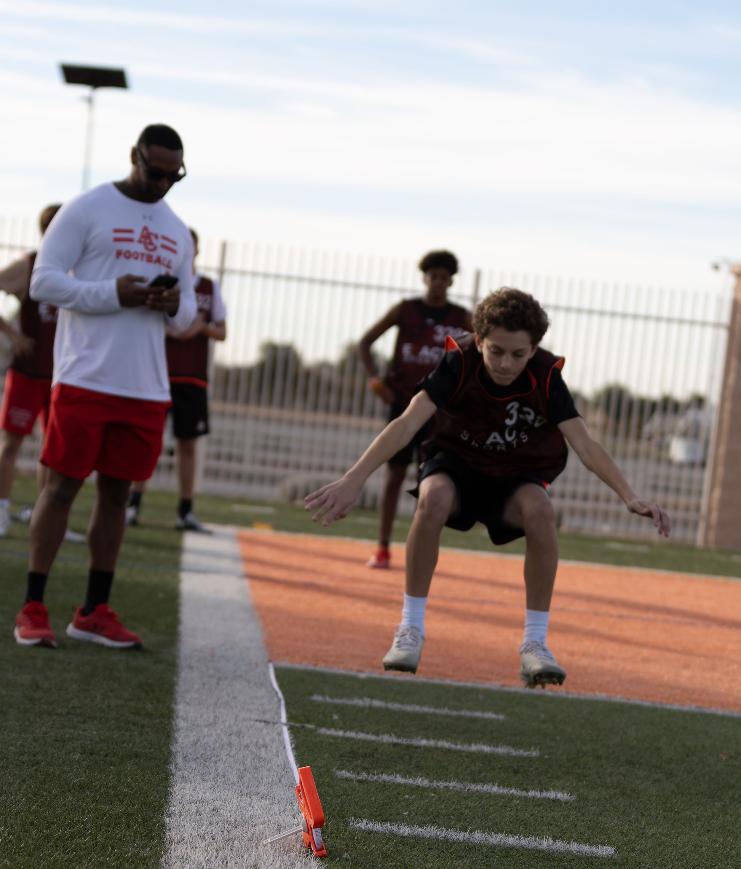 Young athlete in number 33 jersey performing a speed drill on a track during football practice.