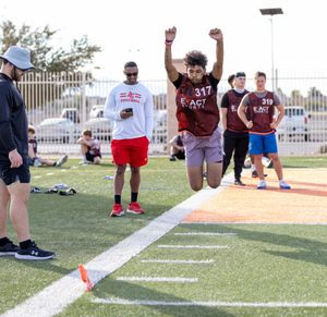 Athlete number 317 executes long jump at Exact Sports football combine on turf field.