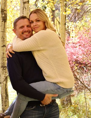 A happy couple embracing among colorful autumn aspen trees in a warm fall setting.