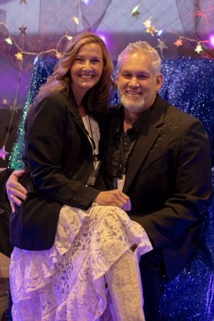 Smiling couple poses together in black formal attire at Night to Shine gala event.