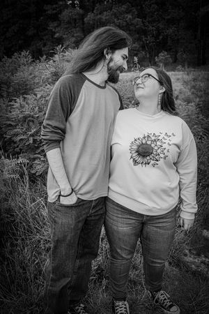 Couple sharing a tender moment in a field, black and white photo with sunflower sweatshirt.