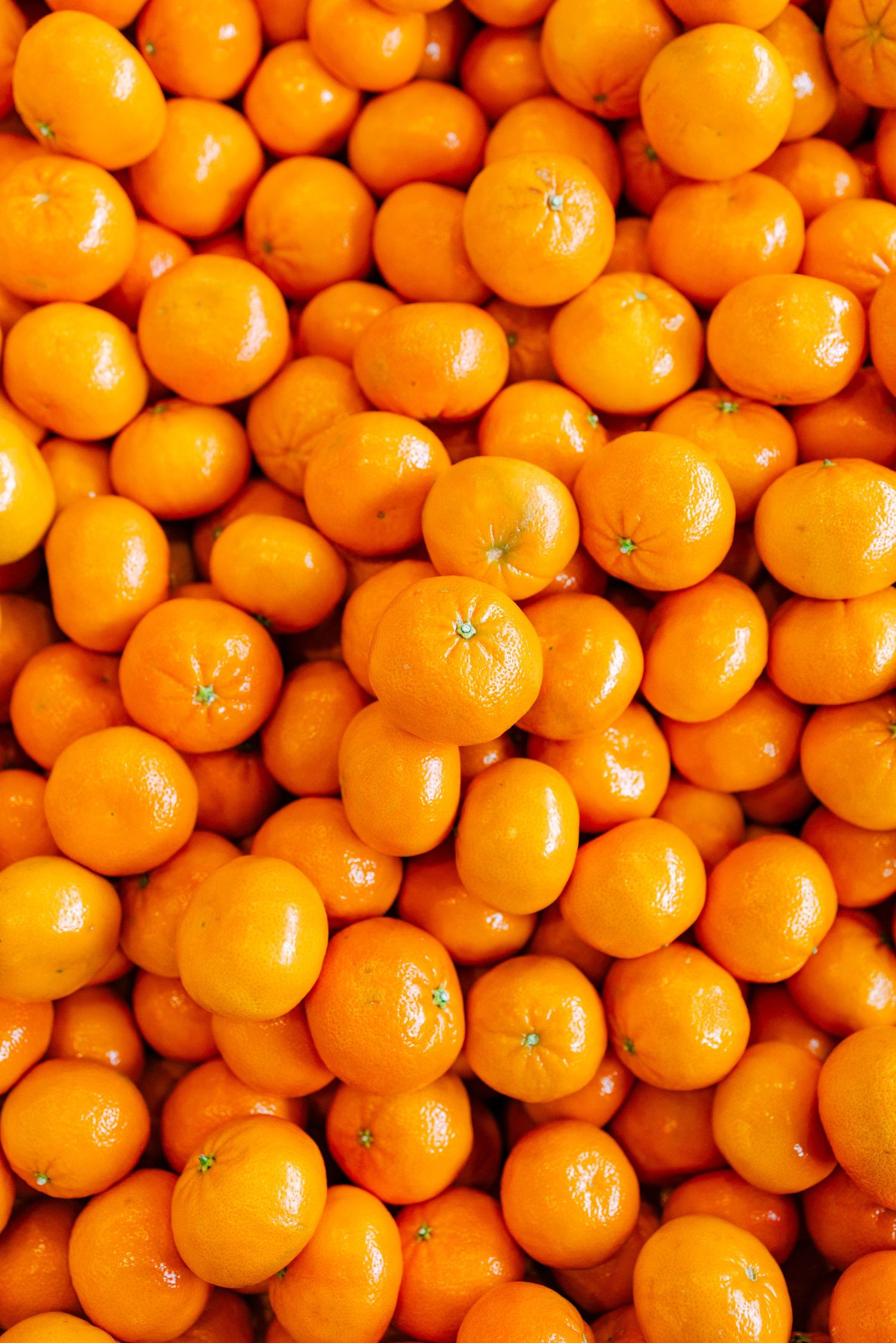 Fresh mandarin oranges creating a vibrant orange background pattern.