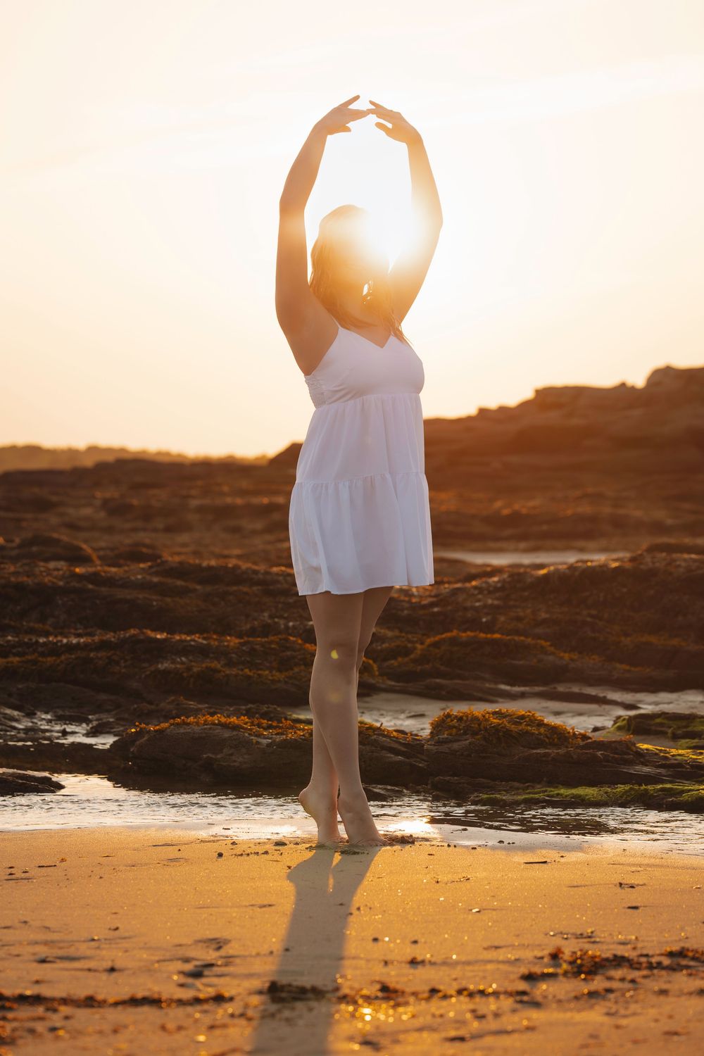 A serene sunrise at a rocky beach with a person in white dress holding a glowing orb, captured in a sequence of frames.