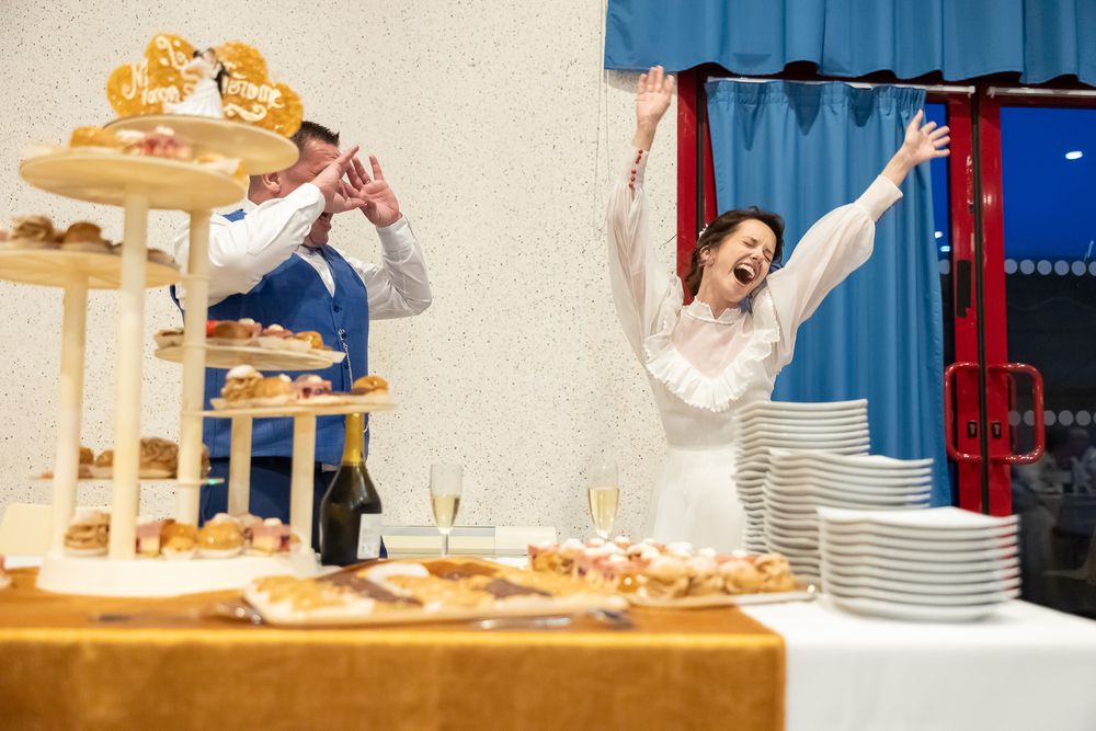 Playful celebration near a dessert display table with decorative treats and stacked plates.