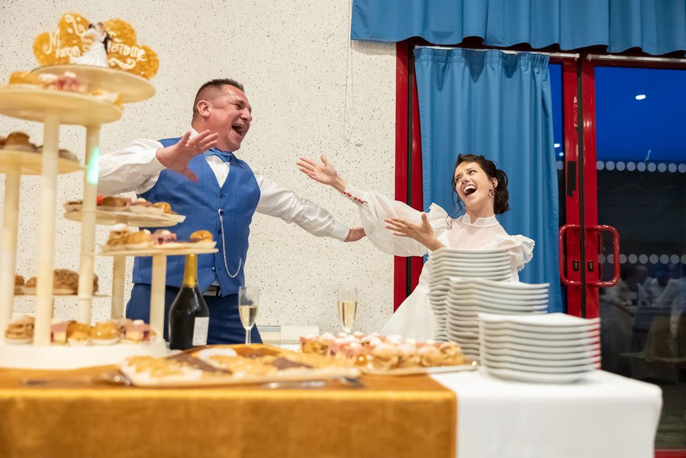 Joyful reactions at a wedding reception dessert table with tiered displays.