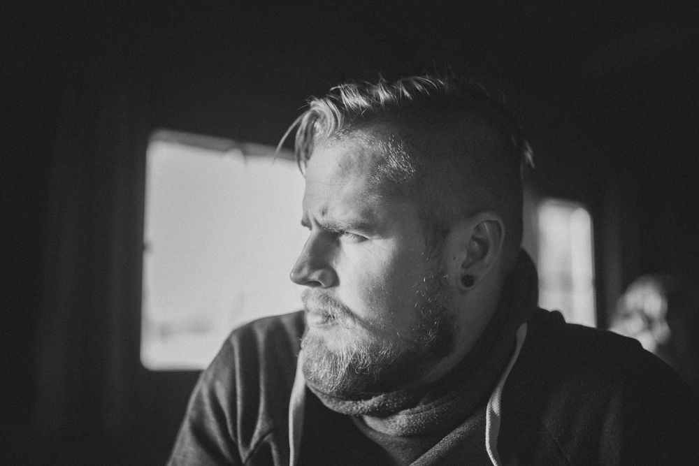 A black and white profile portrait showing thoughtful expression and beard. Professional photographer.