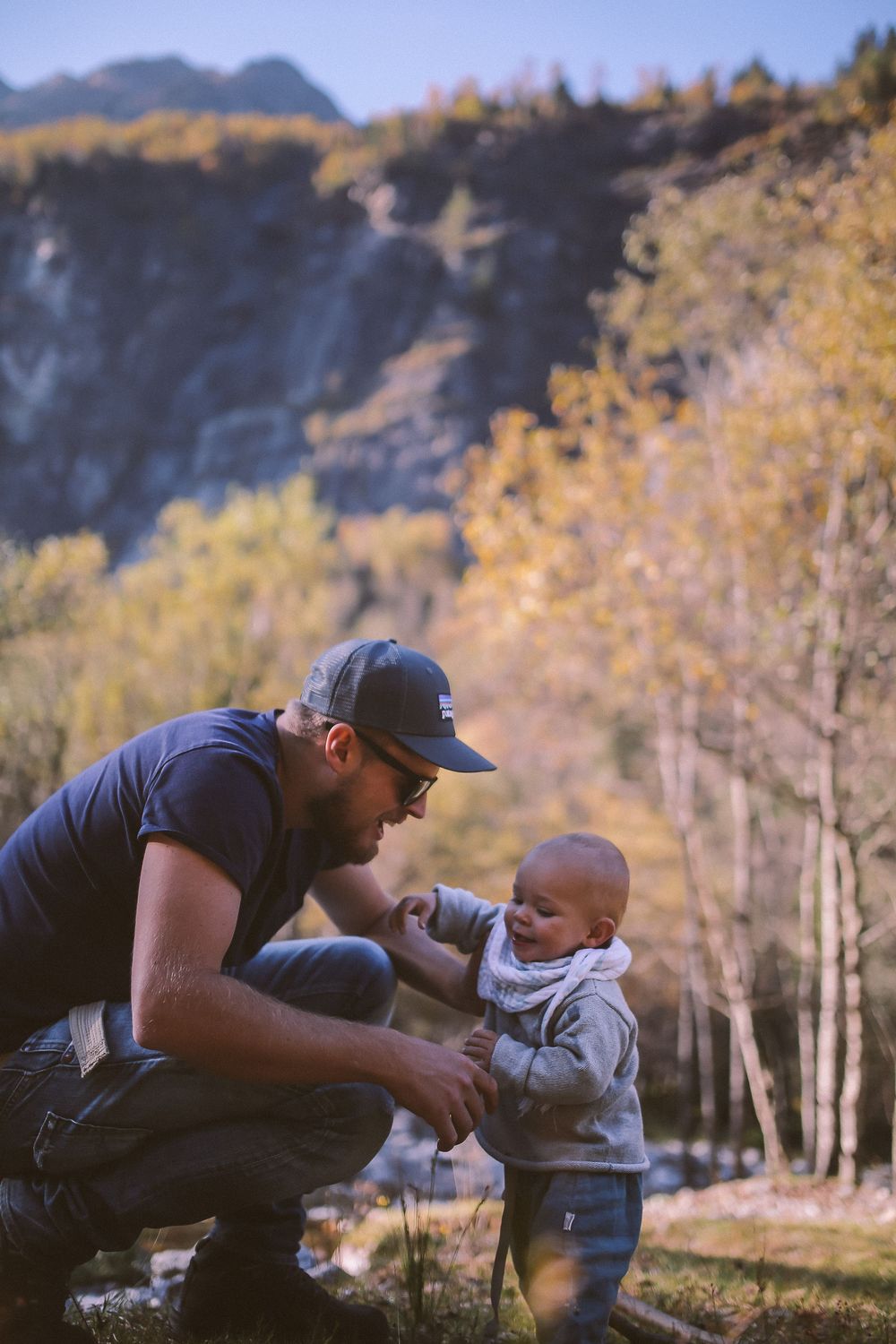 A heartwarming outdoor scene with mountains and fall foliage in the background. Son and father.