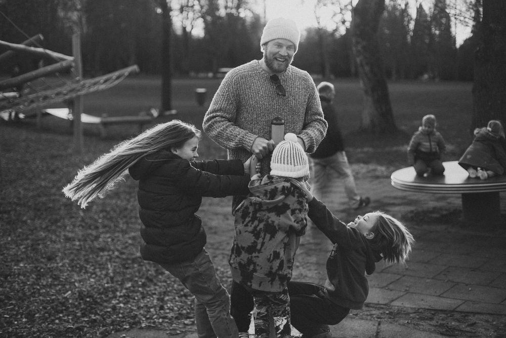 A playful moment at a playground with children being lifted into the air. Family photography.