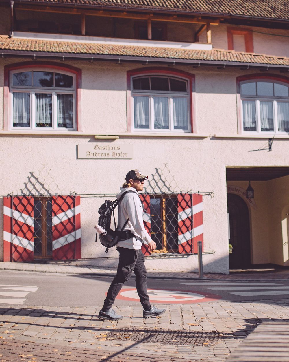 Person with backpack walking past traditional European building with striped decorative elements.