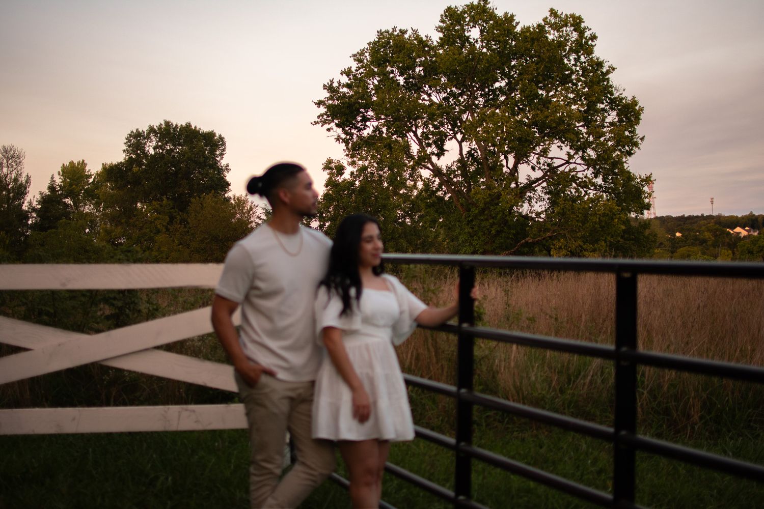 Couple shares a romantic moment against sunset sky on wooden deck.