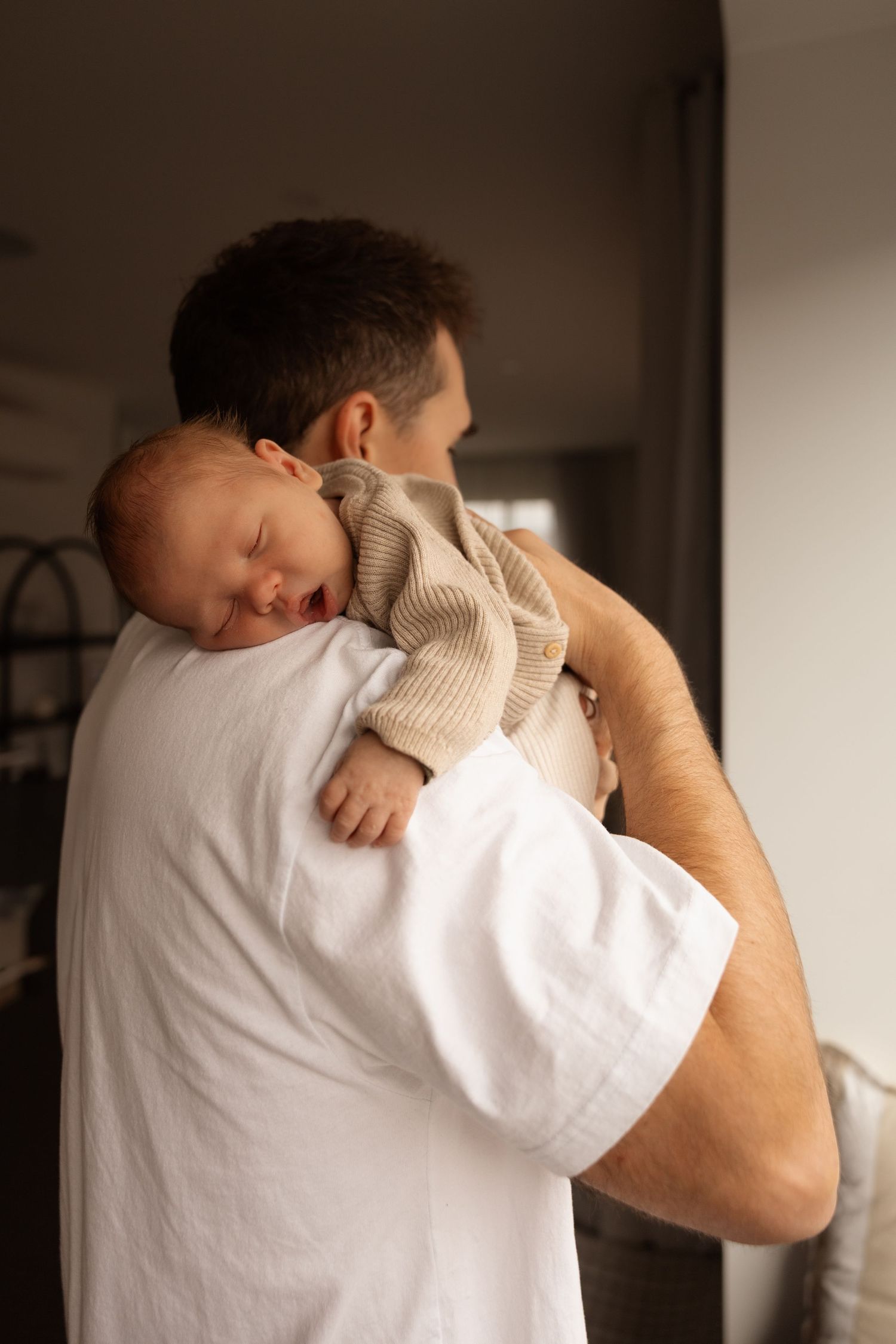 in home newborn session, in christchurch dad holding onto baby sleeping
