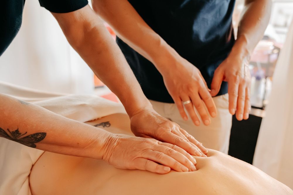 Professional massage therapist performing therapeutic hand movements on a client's leg during a relaxation session.