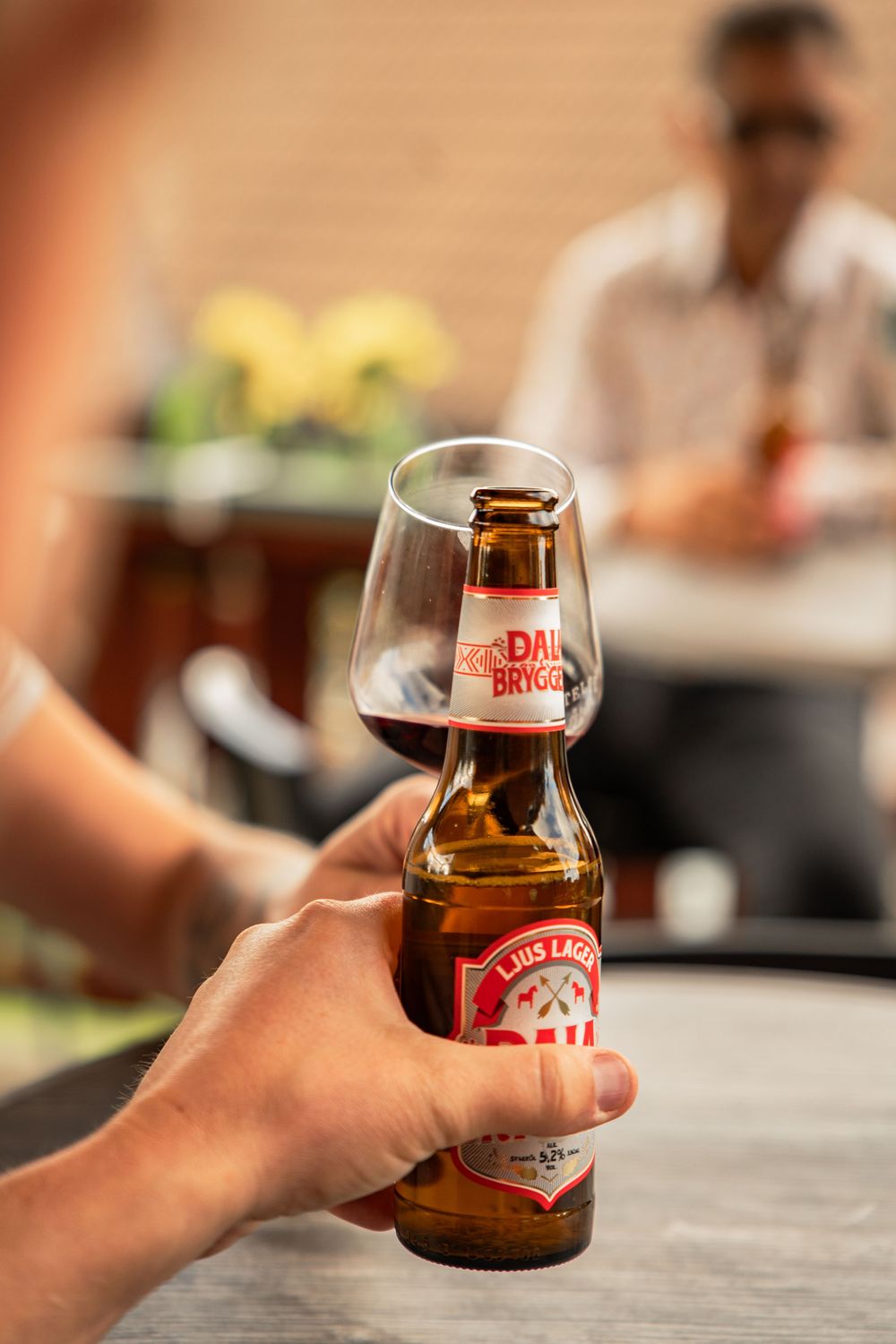 Hand holding a Stella Artois beer bottle with a matching glass in the foreground.