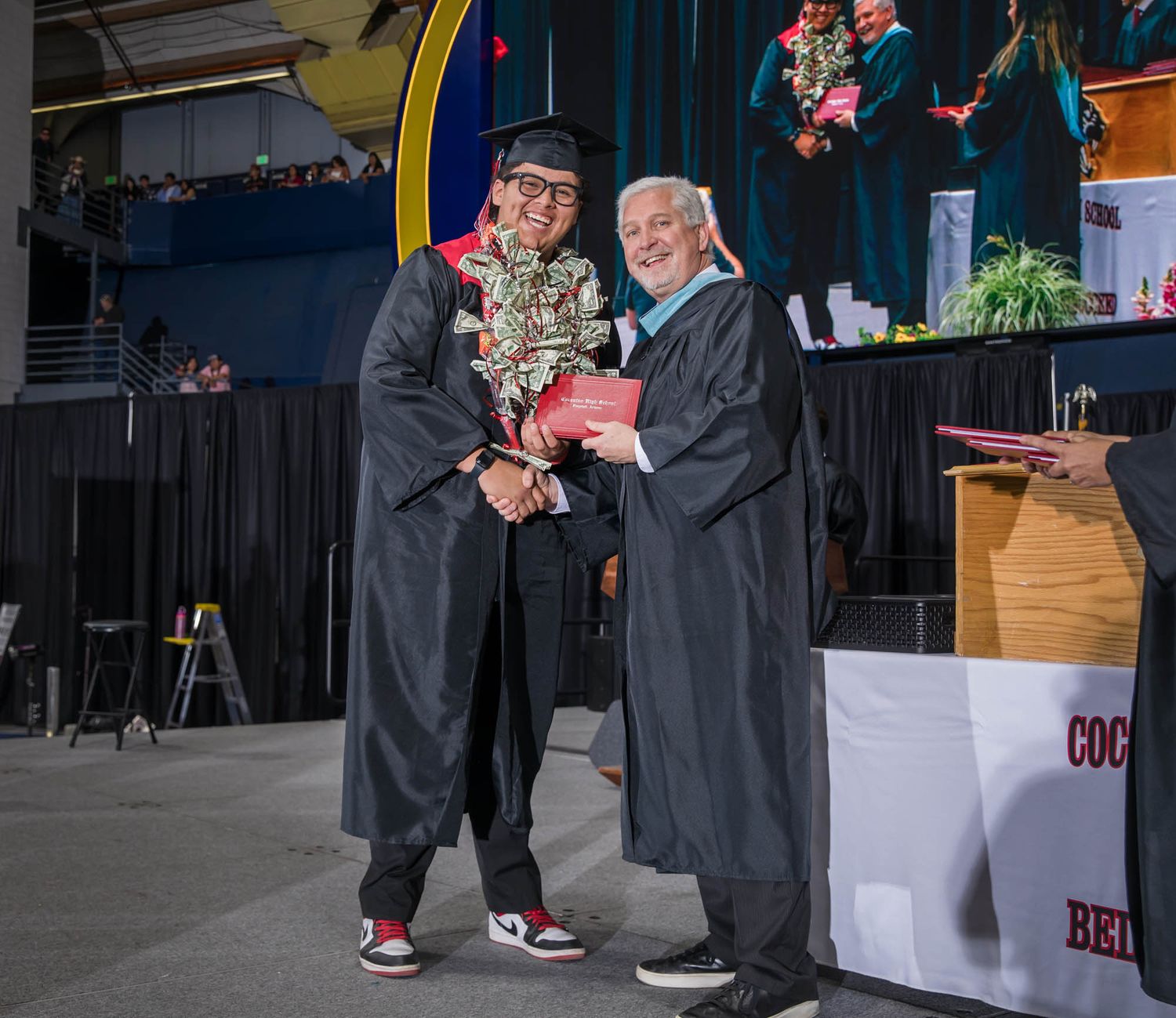 Rober Moreno and Principal Ragan share a moment during a commencement ceremony on stage.
