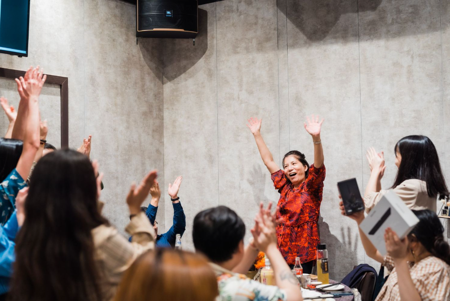 A group of people with raised hands celebrating and having fun at an energetic indoor gathering.