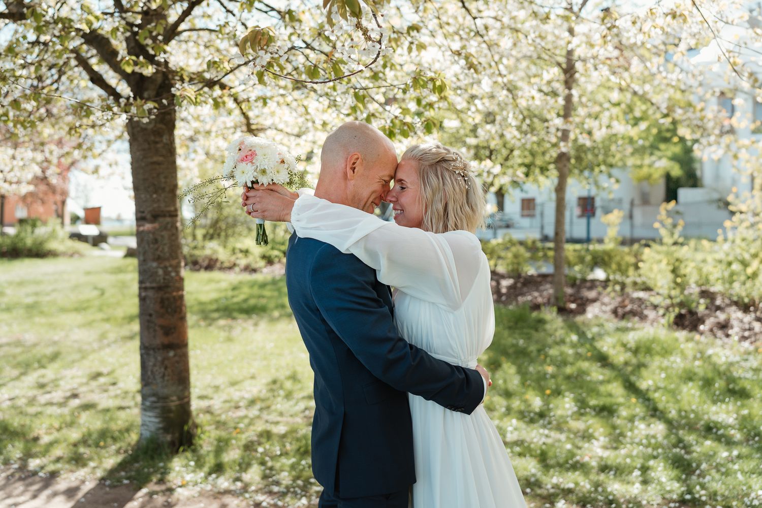 A romantic spring moment shared under blooming cherry blossoms in a sunlit garden.