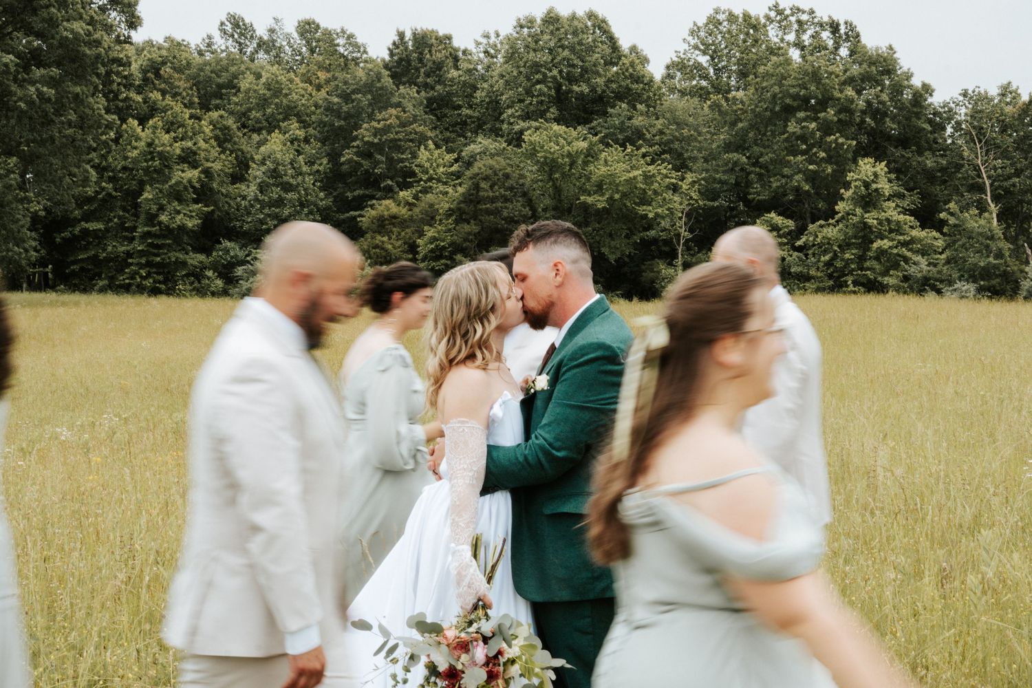 Wedding party celebrating in an open field on a sunny day.