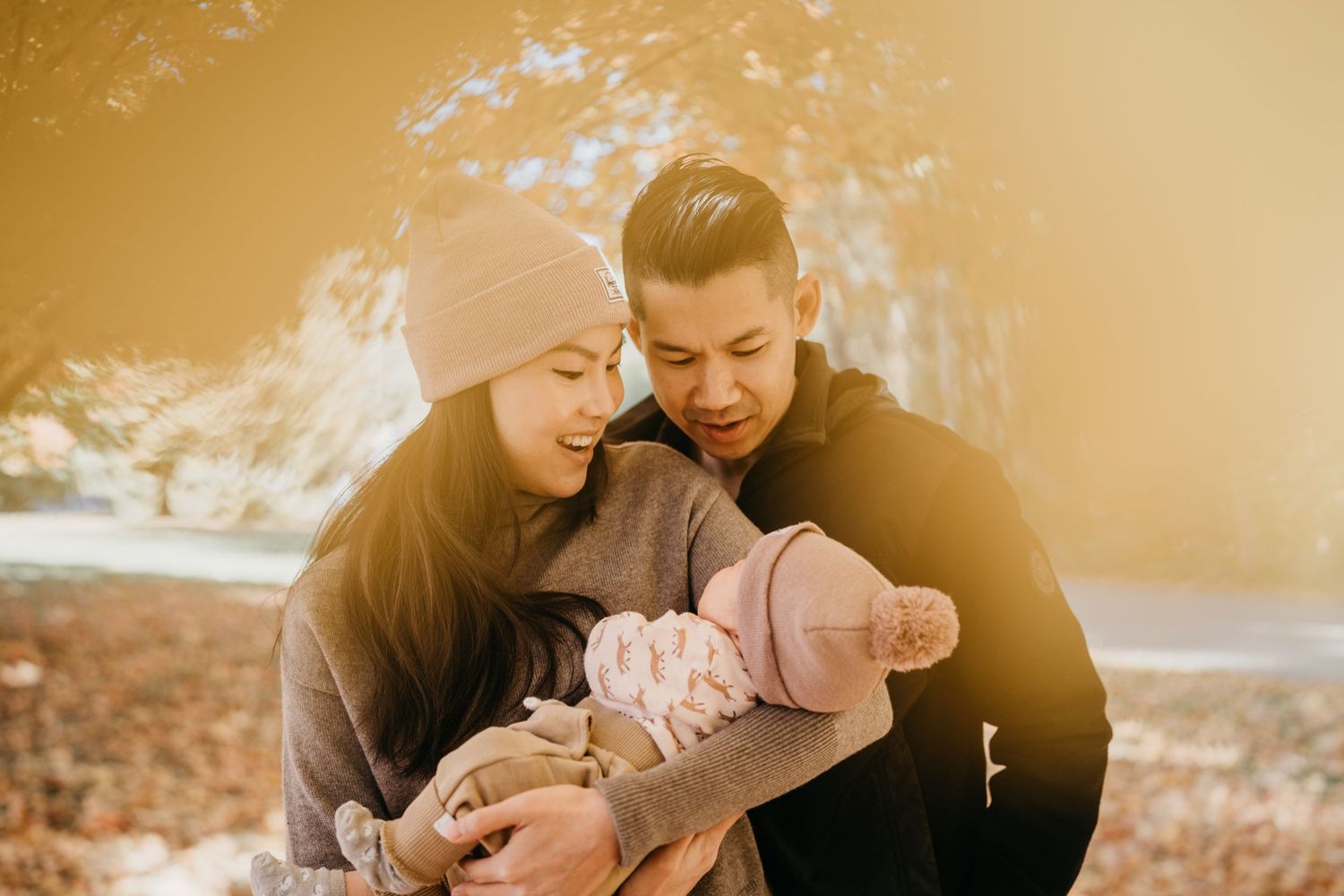 Winter family moment with young infant during golden sunset outdoors.