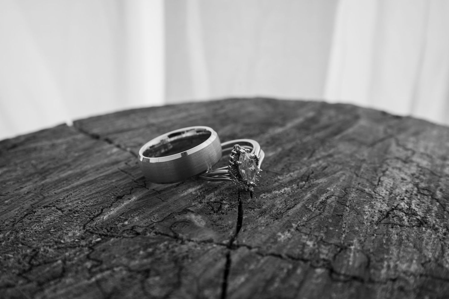 Wedding rings placed on rustic wooden surface in black and white.