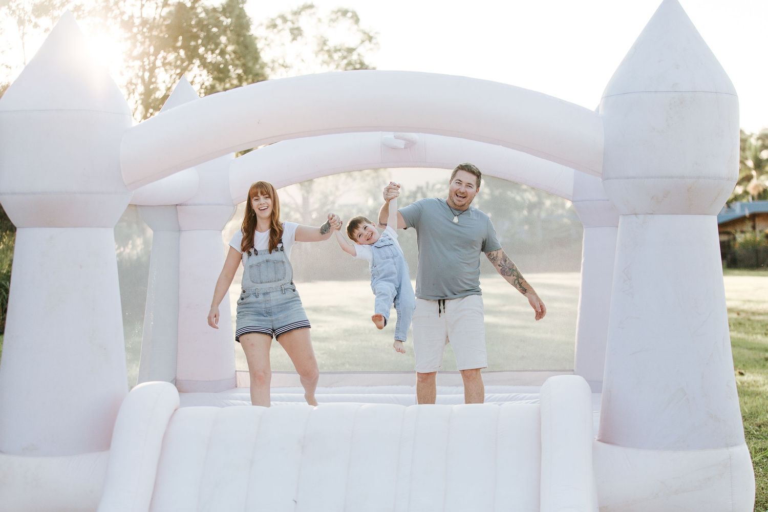 A family jumps together inside a white inflatable bounce castle structure.