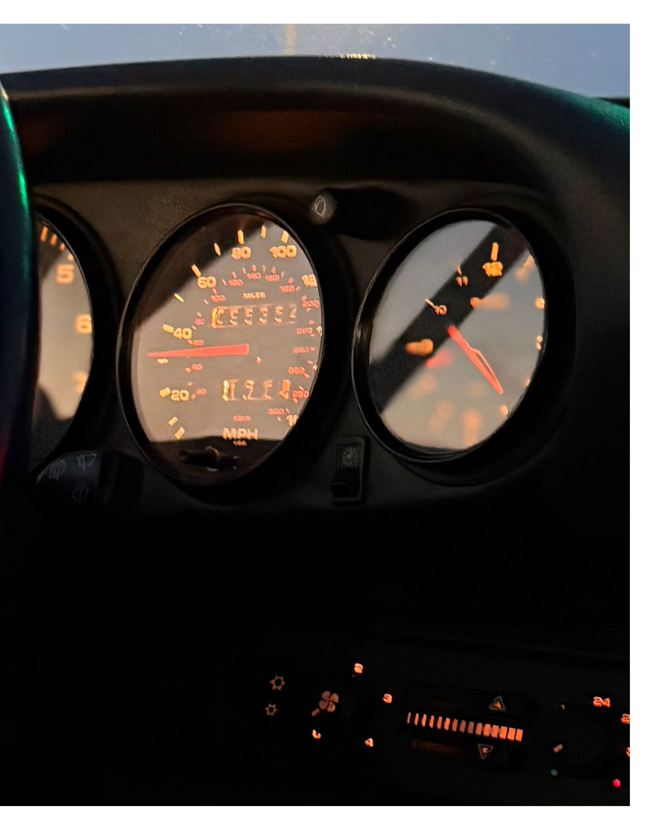 Illuminated dashboard gauges and instrument cluster in dark vehicle interior.