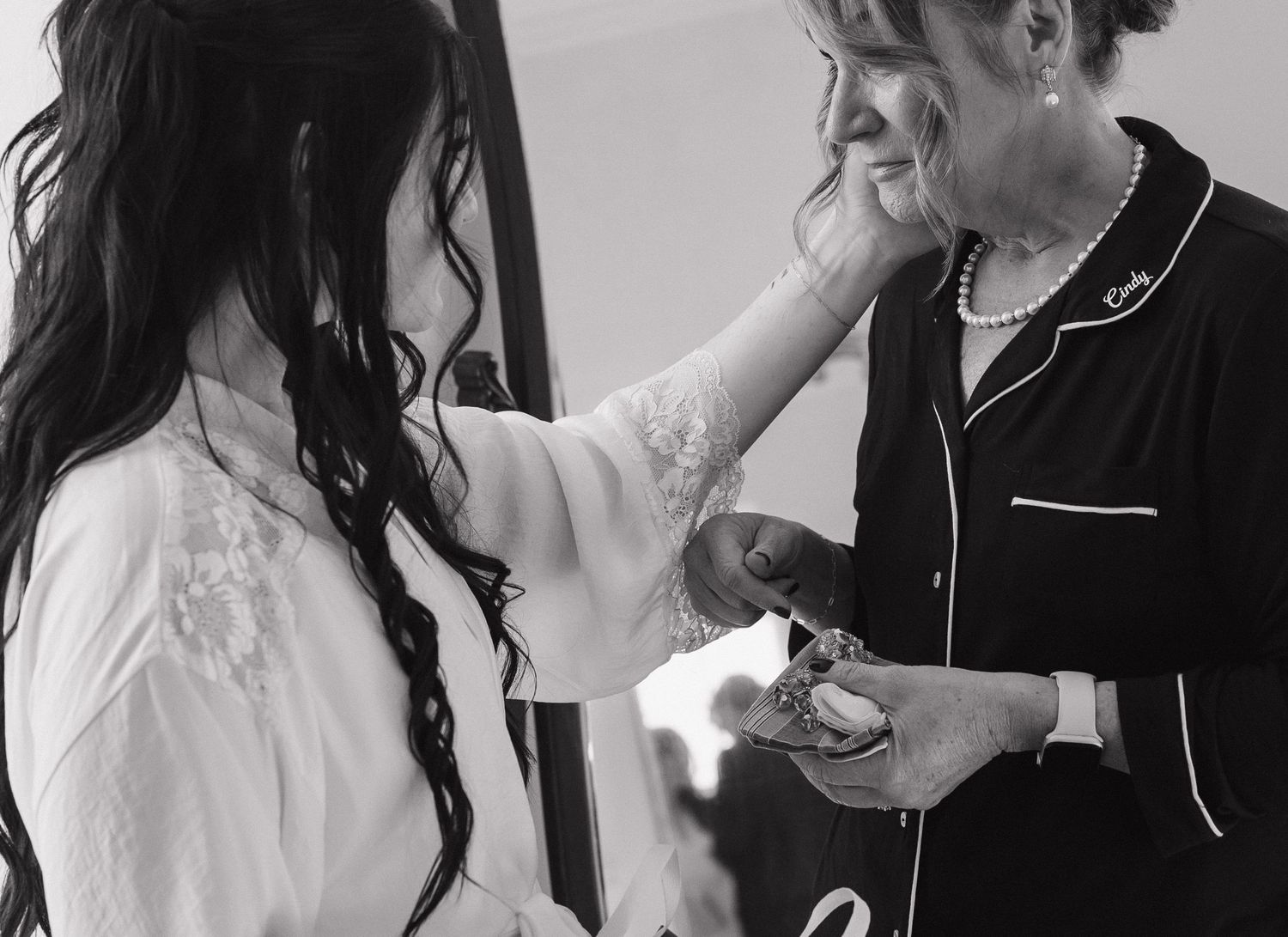 Emotional black and white moment captured as one person wipes away tears while wearing contrasting white and black outfits.