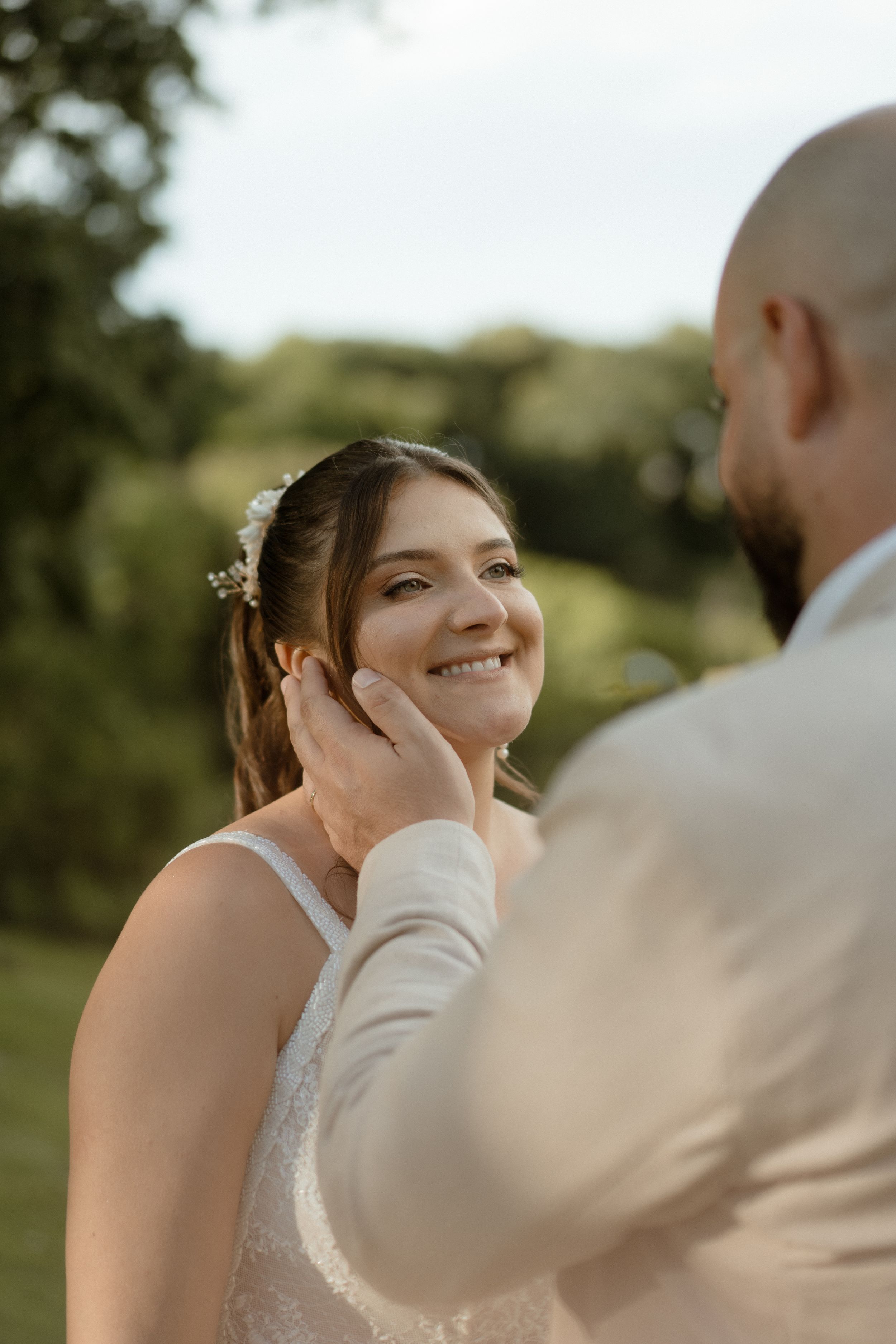 Candid wedding moment captured during outdoor portrait session in golden sunlight.