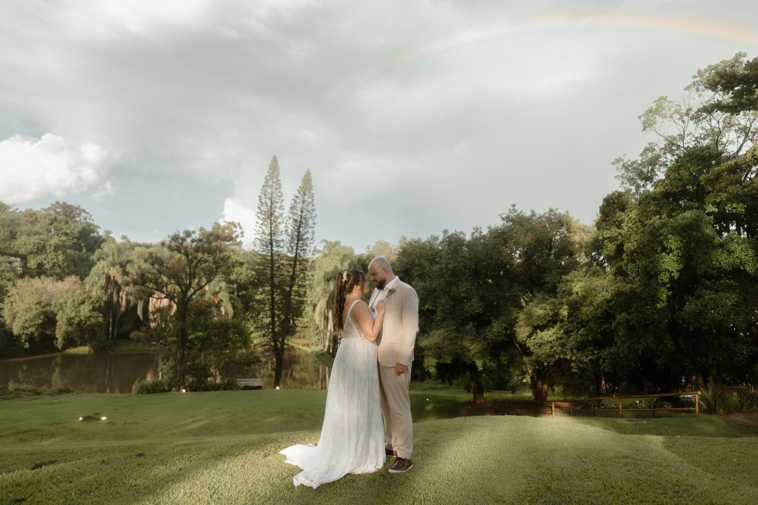 Romantic wedding portrait in garden setting with dramatic cloudy sky backdrop.