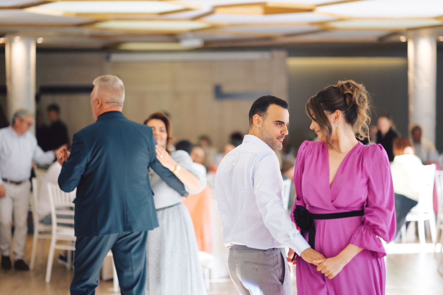 Couples dancing together during a celebration in an indoor venue with soft lighting.