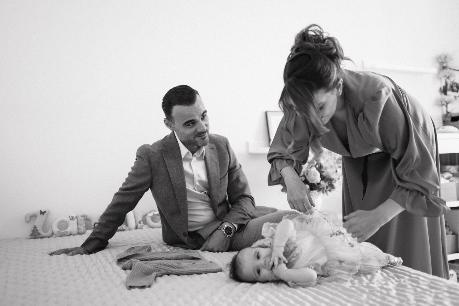 A vintage black and white photograph shows a doctor or healthcare worker examining a baby on an examination table.