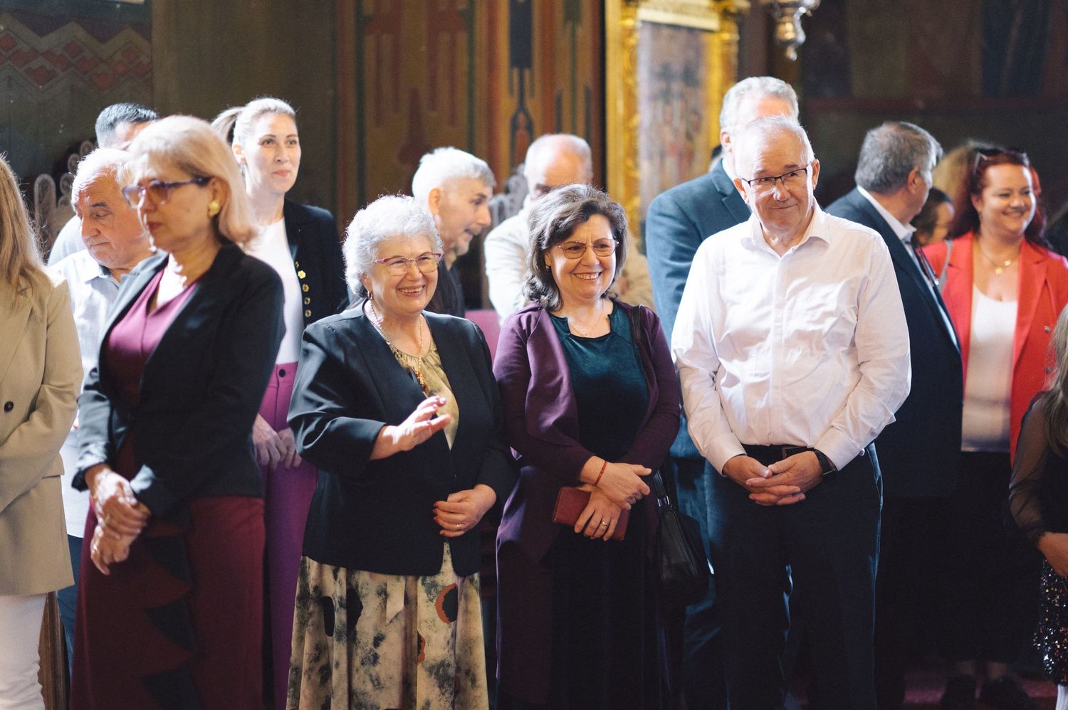 A group of formally dressed people standing together in a line during what appears to be a church or ceremony event.
